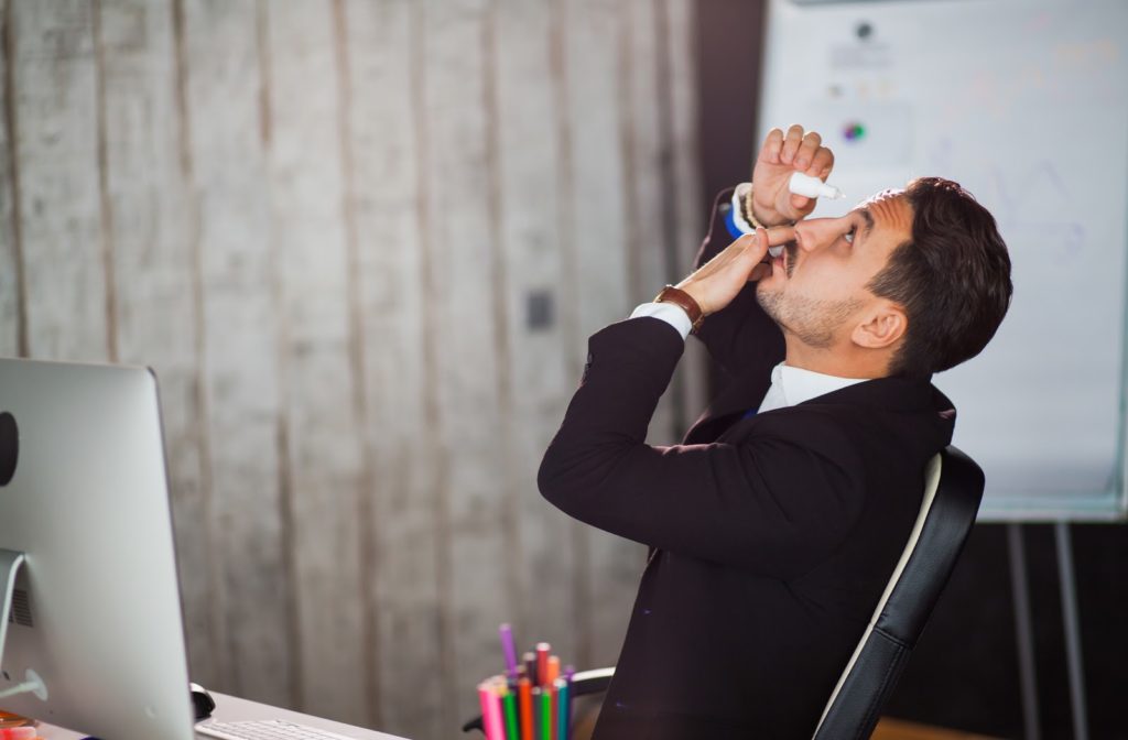 Man using artificial tears to relieve dryness caused by digital eye strain