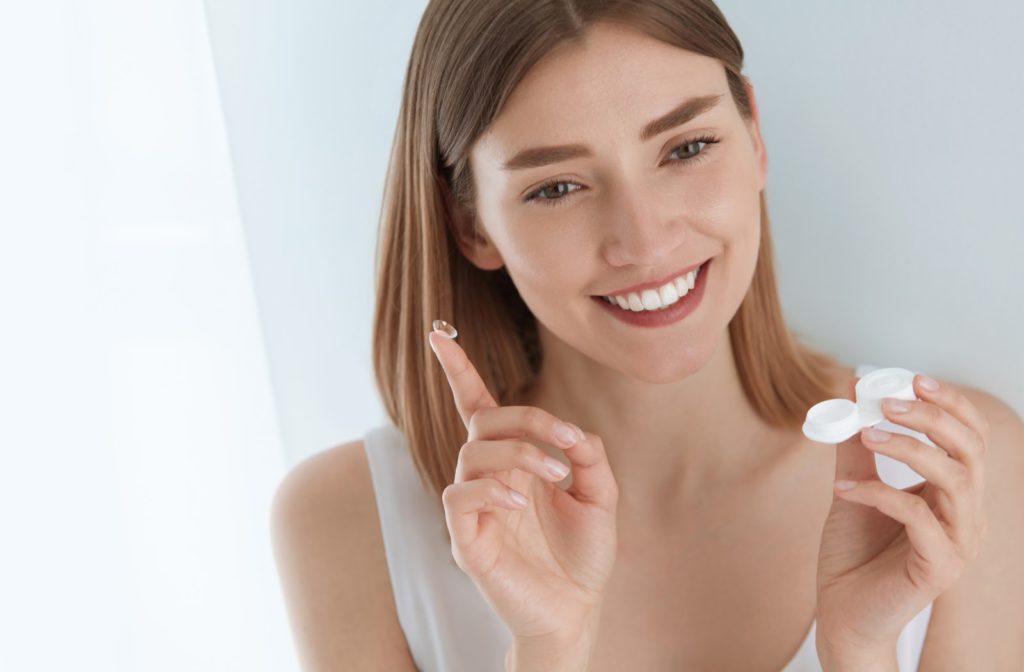 Young happy lady put in her contact lenses into her eyes