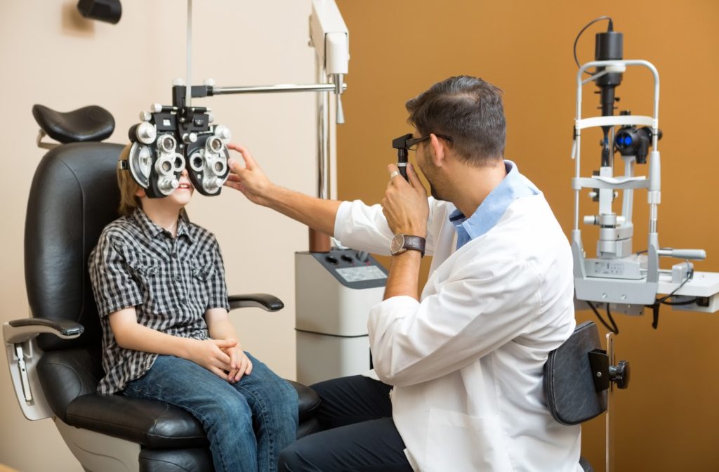 Optometrist performing eye exam on young boy