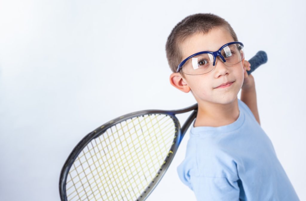 Young boy wearing glasses while holding squash racquet