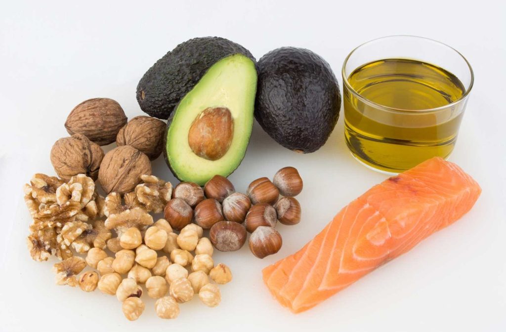 Fish, avocado, and nuts displayed on white background to show omega 3 foods for dry eyes.