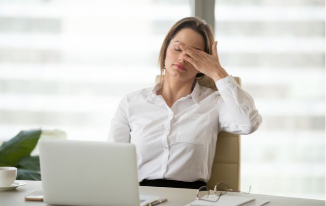 Business women experiencing dry eye due to hormonal change while working on her desk
