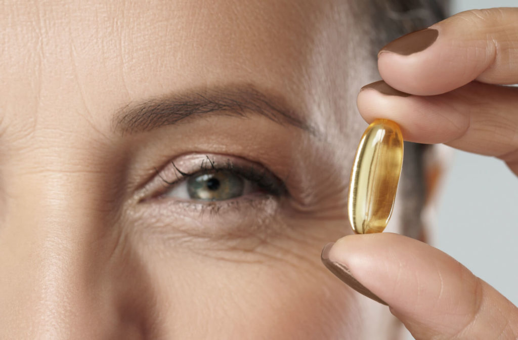 A beautiful middle-aged woman holding a capsule with a fish oil a source of Omega-3 fatty acids