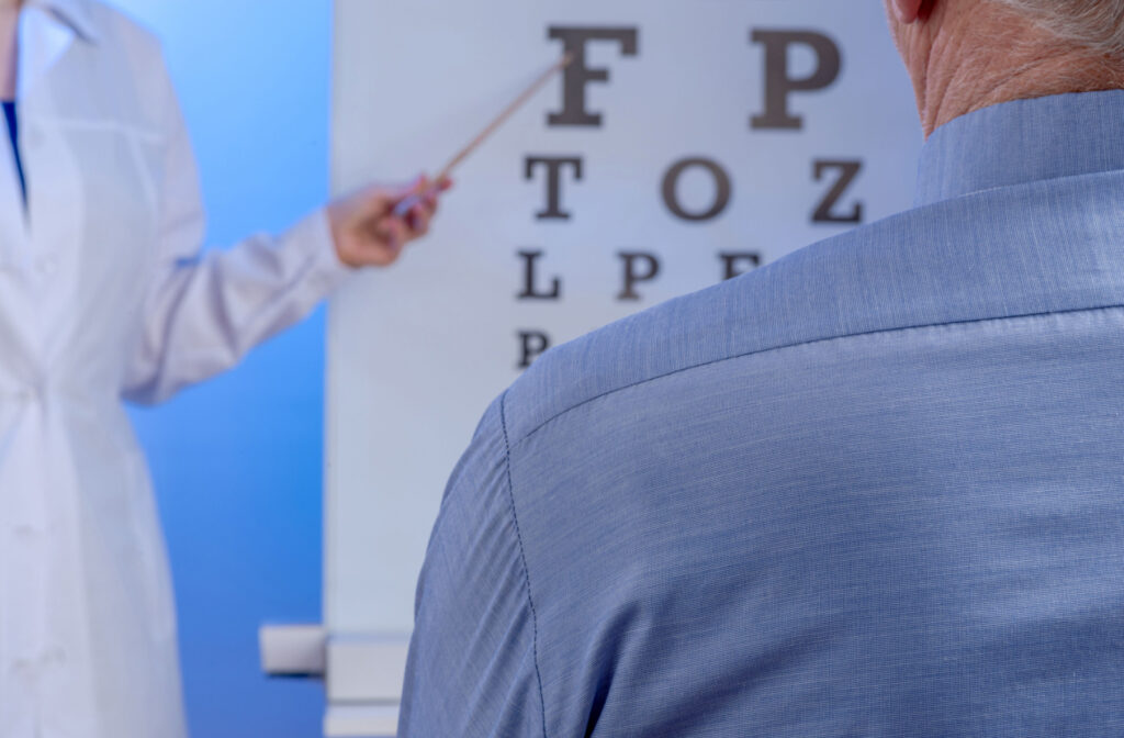 An optometrist pointing to an eye chart that their patient is reading